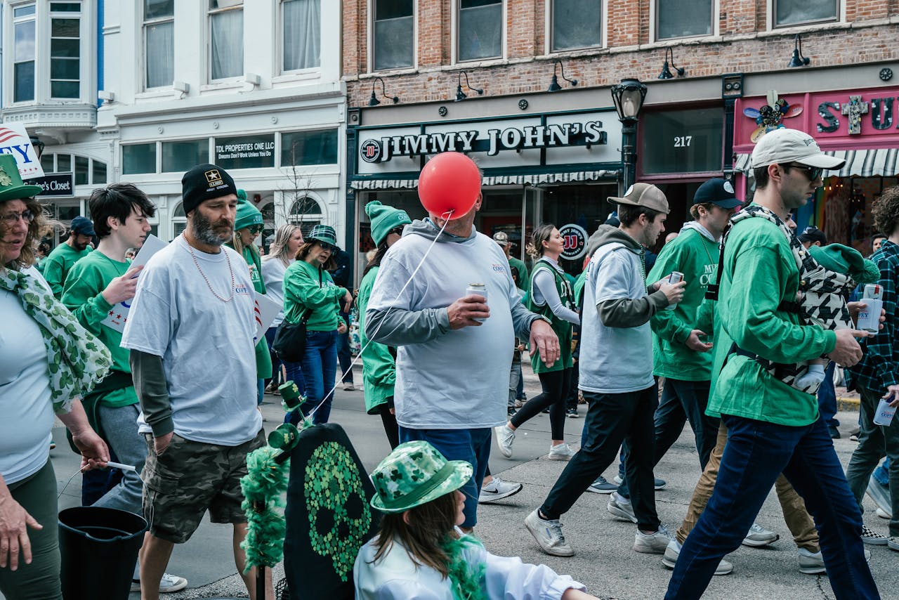 A group of people walking down a street with green hats